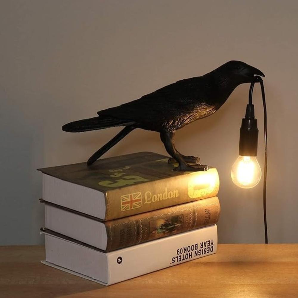 Gothic crow lamp in resin and iron holding a glowing bulb