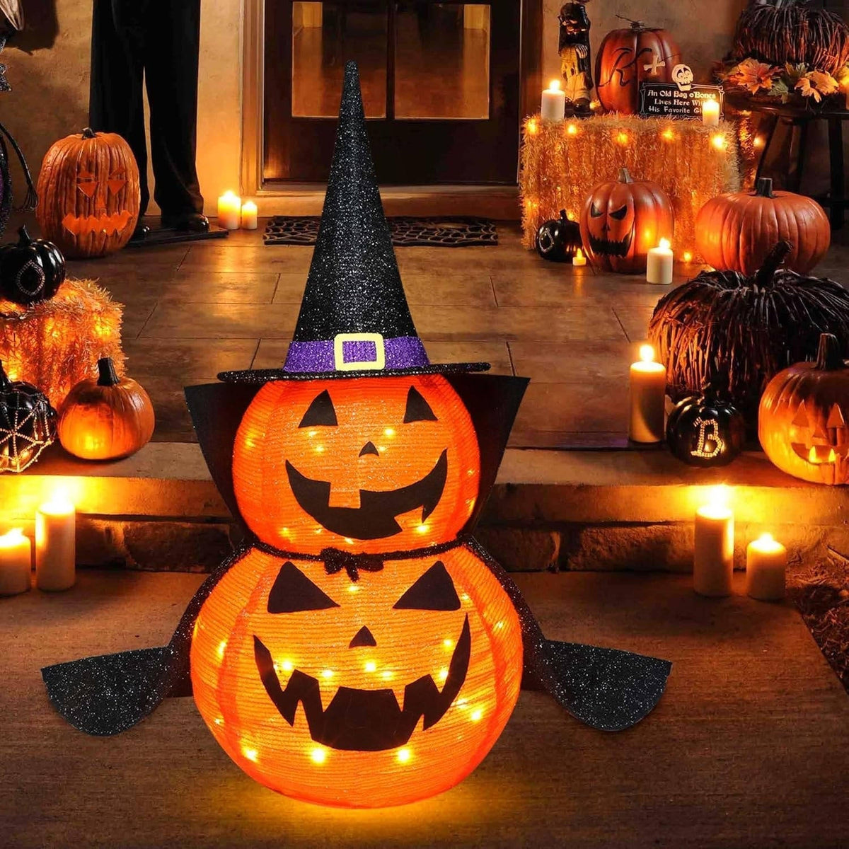 Pair of 3 foot lighted Halloween pumpkins with wizard hats glowing on a lawn