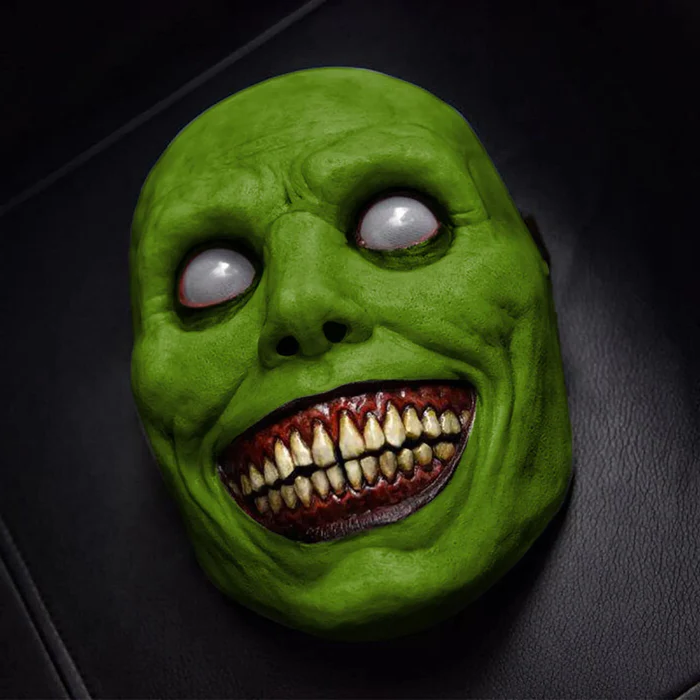 Green evil grinning demon Halloween mask with yellow teeth and white eyes