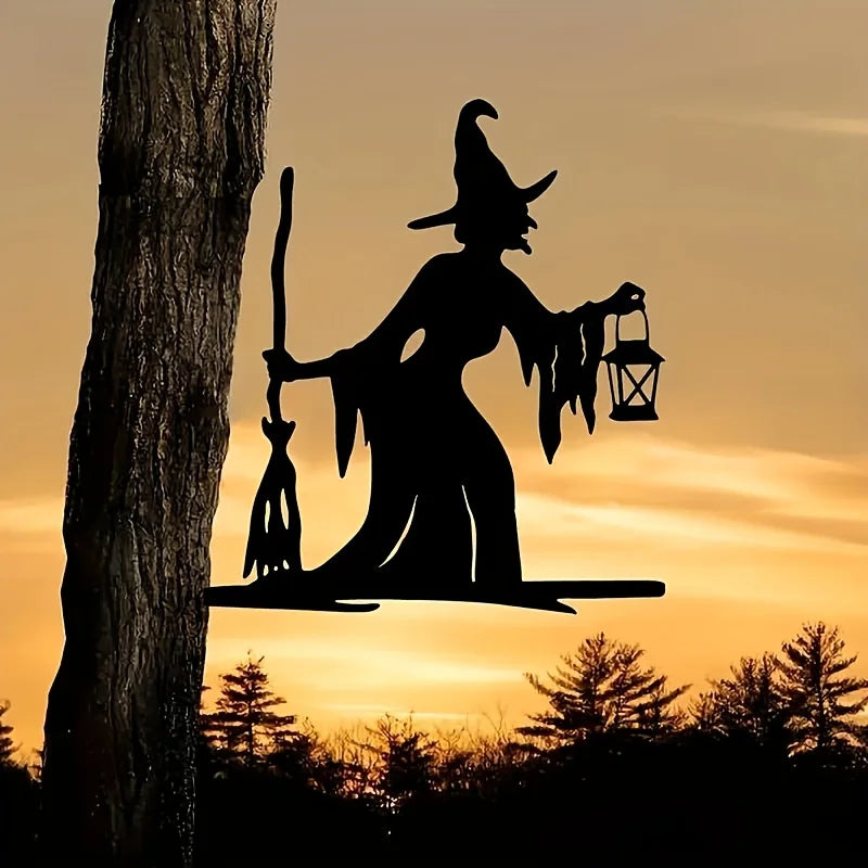 Iron witch silhouette garden stake standing in a yard