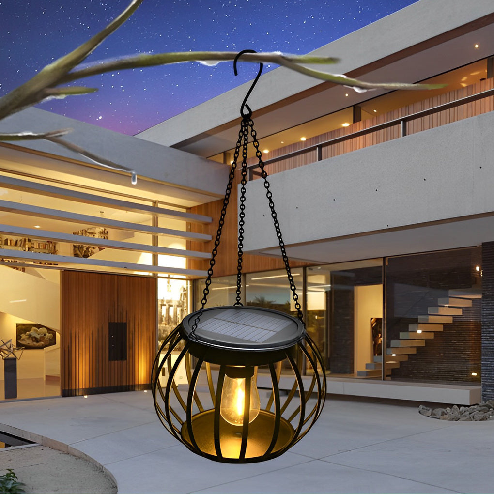 Black metal pumpkin solar lantern glowing outdoors at night