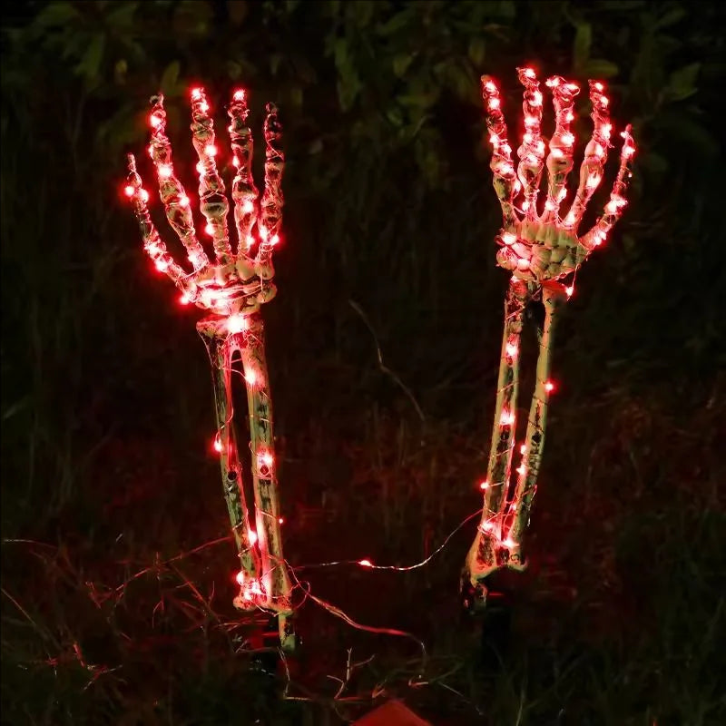 Solar Halloween skeleton hand stake light glowing orange in a yard