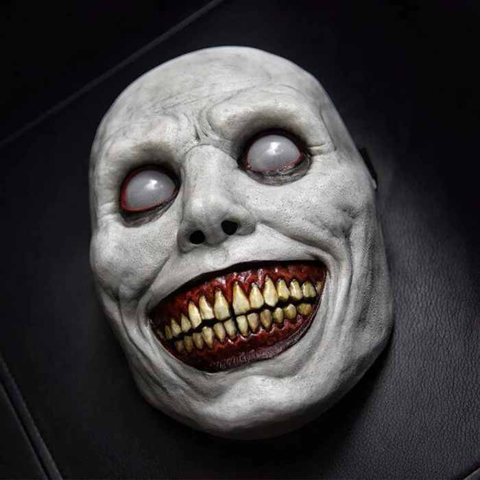 White evil grinning demon Halloween mask with yellow teeth and white eyes