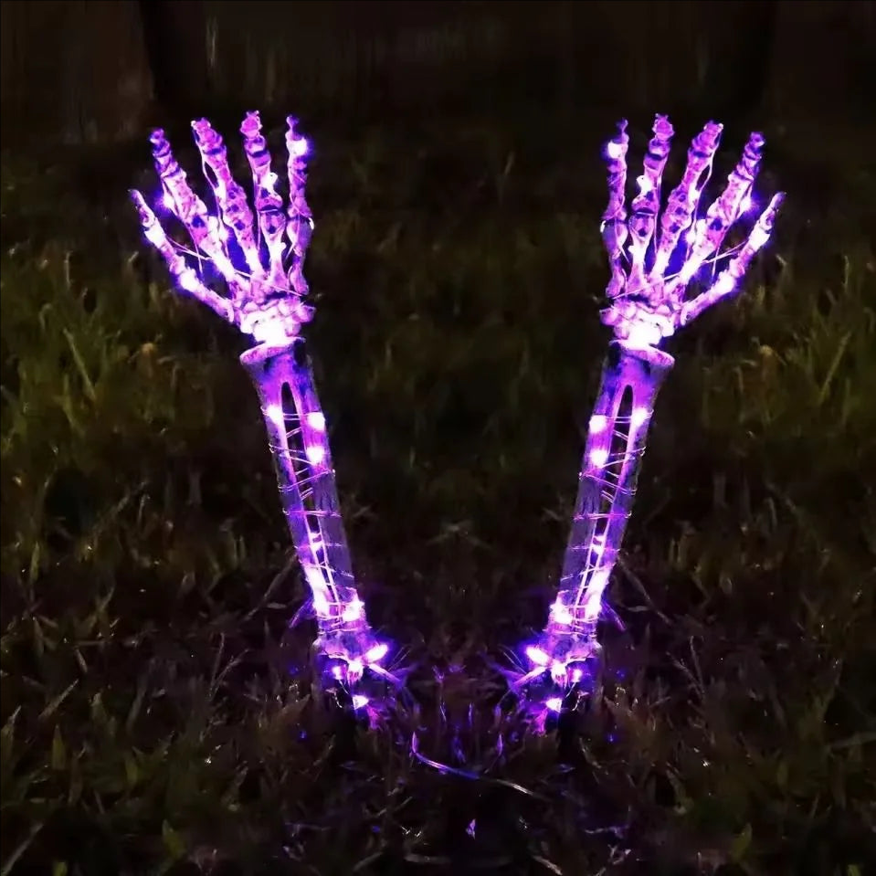 Solar Halloween skeleton hand stake light glowing purple in a yard