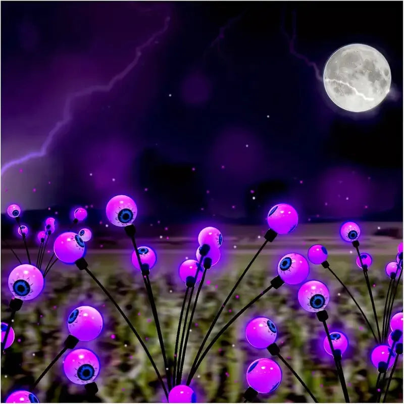 Solar Halloween eyeball garden lights glowing purple on a lawn