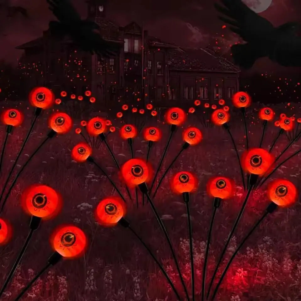 Solar Halloween eyeball garden lights glowing red in a flower bed