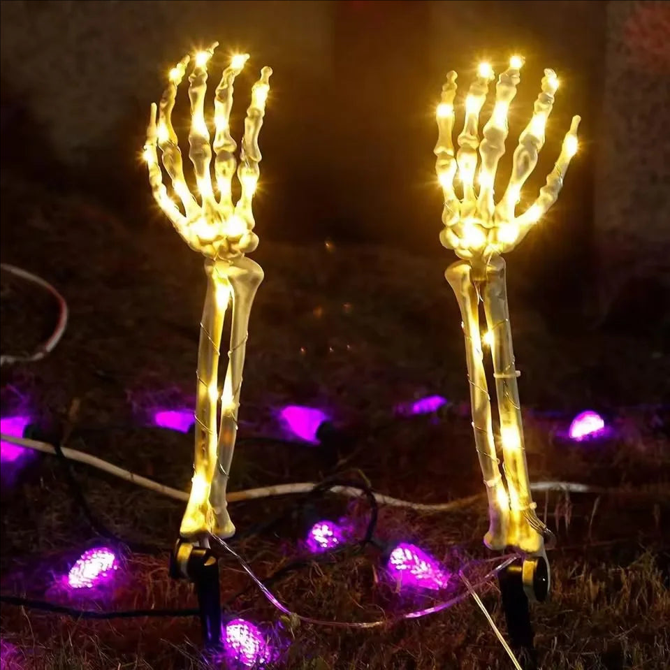Solar Halloween skeleton hand stake light glowing warm white in a yard